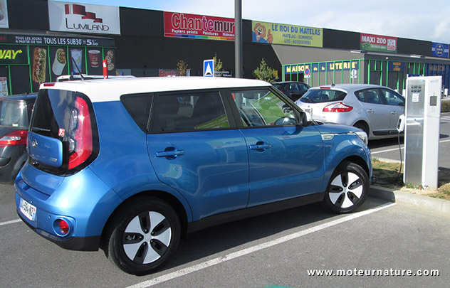 Kia Soul EV devant la borne de charge de la zone commerciale Champea